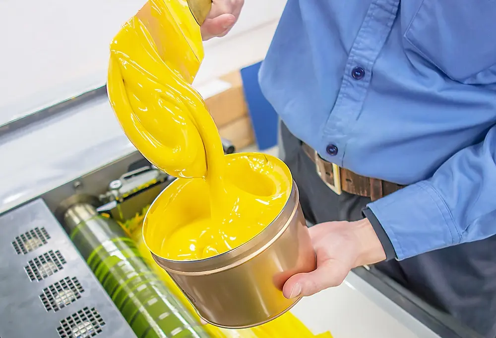 Technician adding ink to a printing press